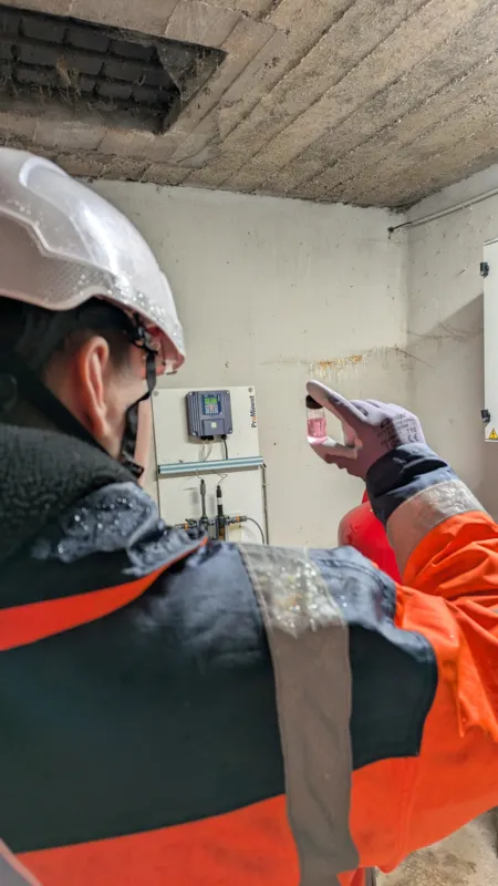 Technicien réalisant un dosage de chlore dans l'eau potable à Fépin, en fond se trouve l'analyseur en continu. Décembre 2024.